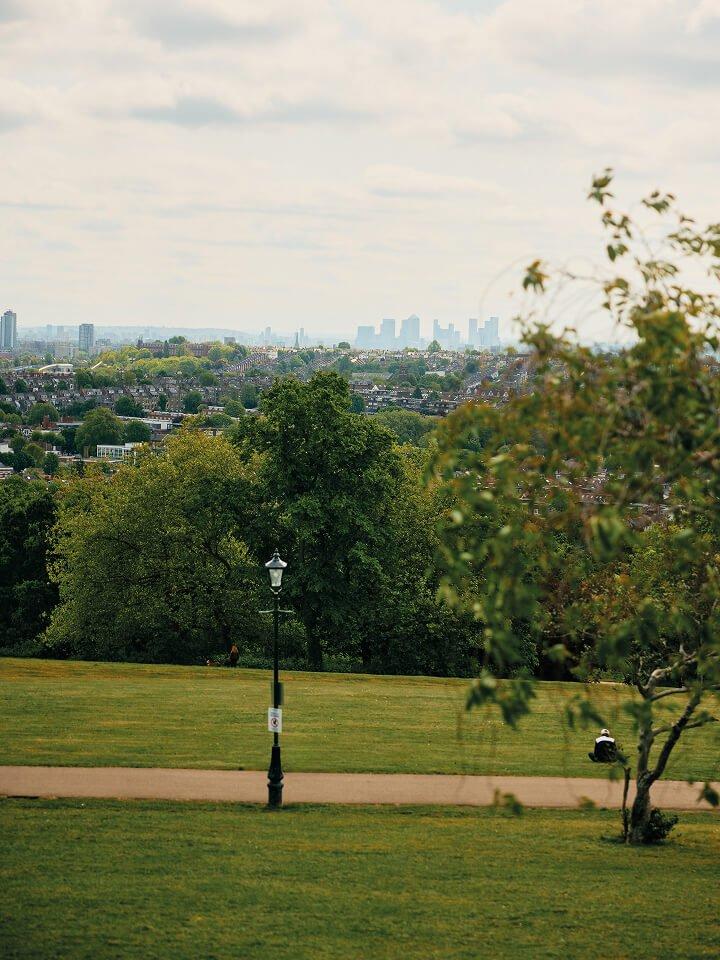 a man sitting on a grassy field with a city in the background